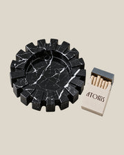 Aston Ash Tray beside an ATOMS pack and stone cigarette styling props; the pack and props are not included.