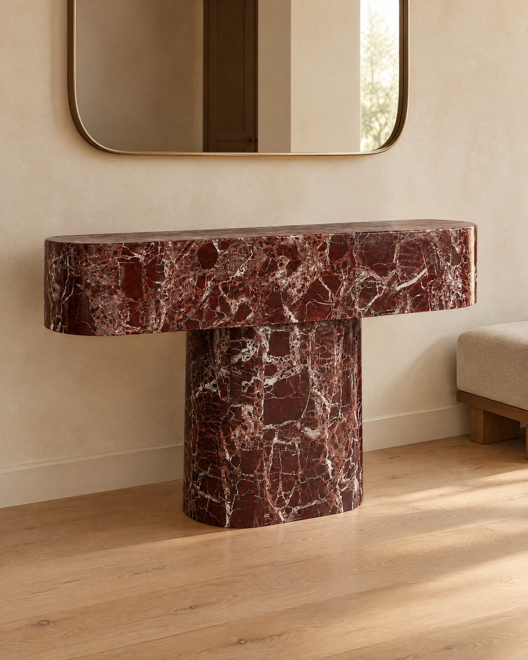 BUTTER console table by CARVINGS in Rosso Levante Marble, in a styled interior, left view.