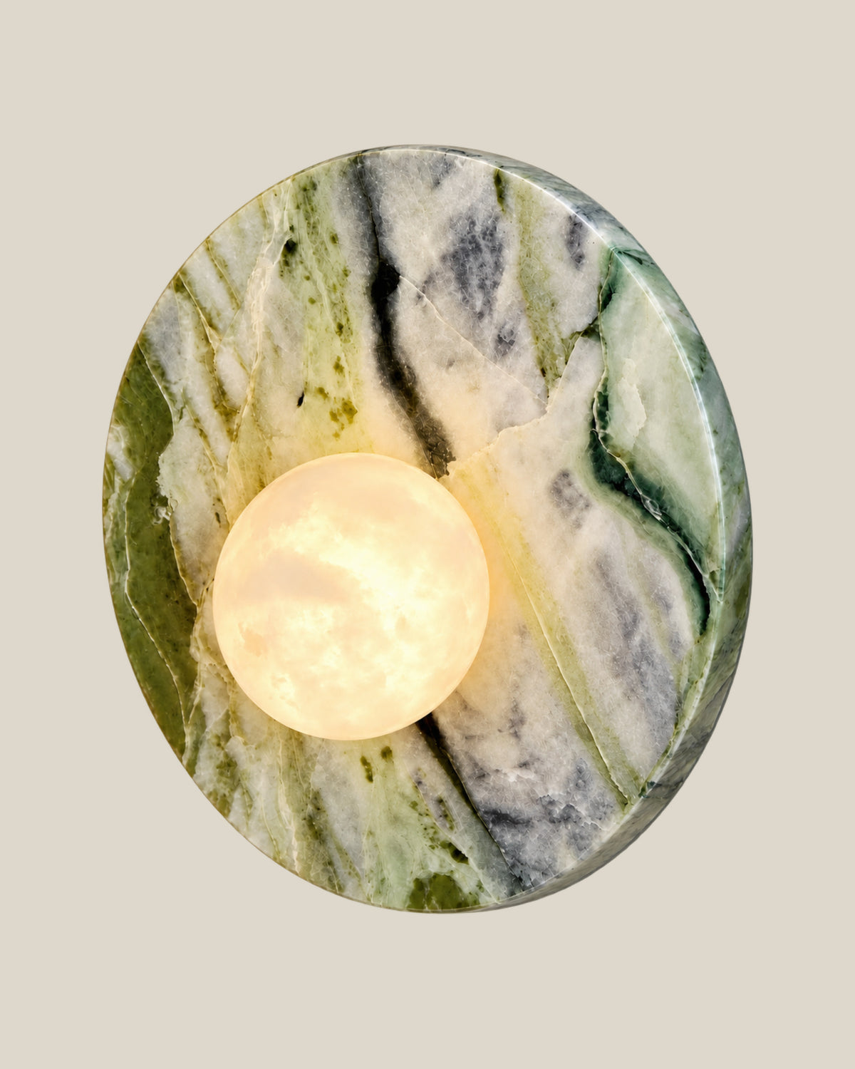Right angled view of LUNETTE Wall Light showing the Ice Jade marble backplate and glowing globe.