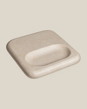 PAD Tray in beige natural stone, high-angle view showing the broad flat surface and elongated oval recess.